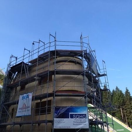 Rundes Gebäude im Bau mit Holzverkleidung und Gerüst - Sprungrichterturm Oberhof