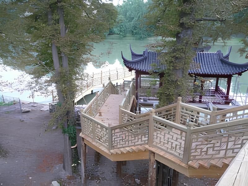 Impression - Holztreppe mit einer Pagode im Hintergrund, umgeben von üppiger Natur.