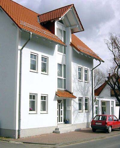 Impression - Weißes Mehrfamilienhaus mit einem roten Auto davor